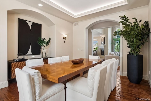 9171 E Harvard Ave, Denver, CO 80231 - dining room featuring dark wood-type flooring, arched walkways, recessed lighting, a tray ceiling, and a fireplace