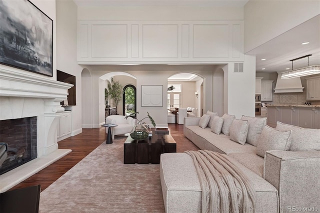 9171 E Harvard Ave, Denver, CO 80231 - living area featuring arched walkways, a fireplace with raised hearth, dark wood-style floors, and recessed lighting
