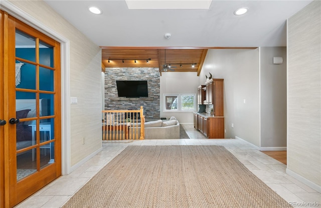 living area with baseboards, track lighting, and a stone fireplace