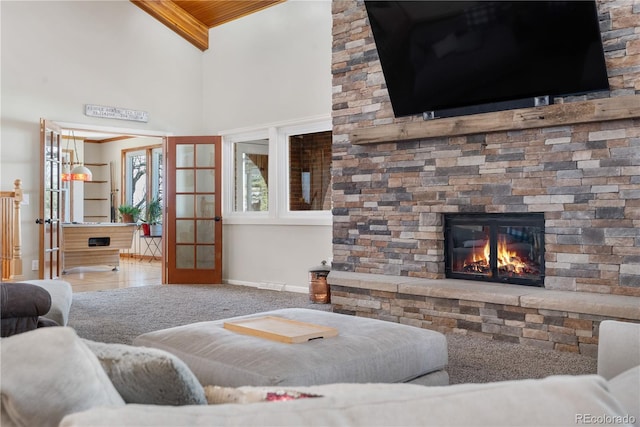 living area featuring baseboards, a high ceiling, a fireplace, and french doors