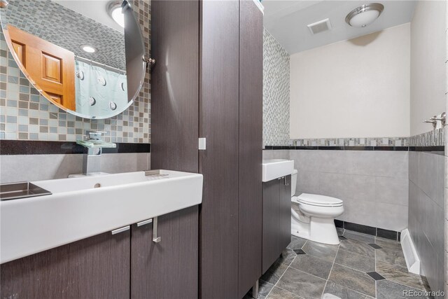 full bathroom with vanity, toilet, tile patterned floors, tile walls, and visible vents
