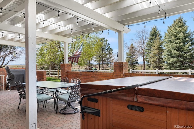 view of patio with a hot tub, fence, and outdoor dining space