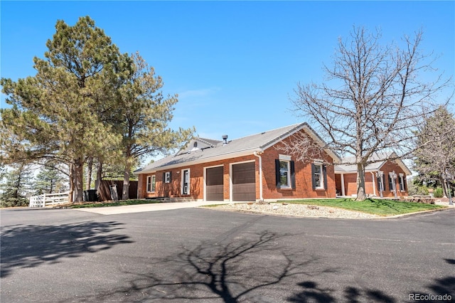 view of front of home featuring an attached garage, aphalt driveway, and brick siding