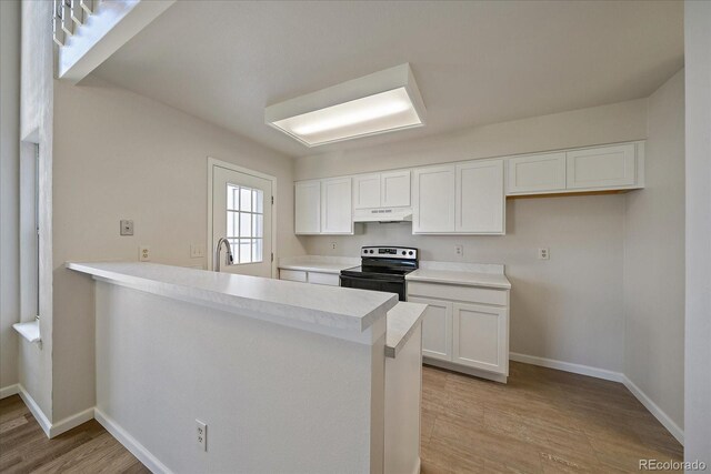 kitchen featuring range with electric cooktop, under cabinet range hood, light wood-type flooring, white cabinetry, and baseboards