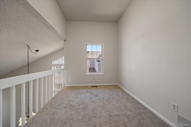 carpeted empty room featuring a textured ceiling and baseboards