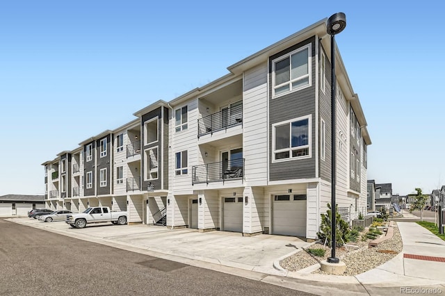view of property featuring central air condition unit, driveway, and a garage