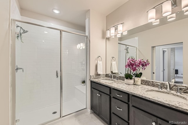 bathroom featuring a shower stall, double vanity, and a sink