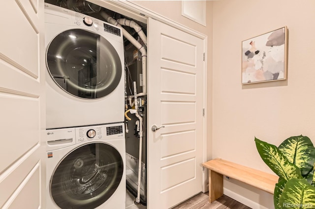 laundry area featuring light wood-type flooring, laundry area, and stacked washer and clothes dryer