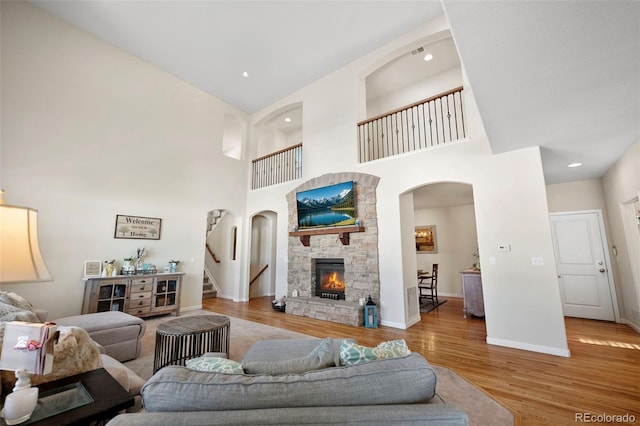 living room with a high ceiling, a fireplace, and light hardwood / wood-style floors