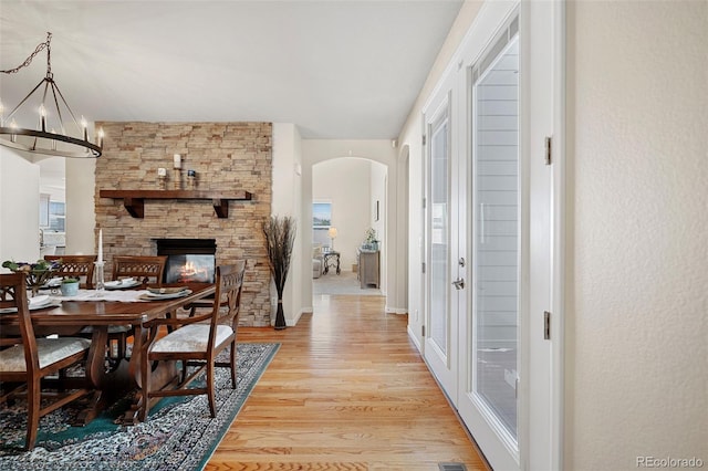 dining space featuring a fireplace, a notable chandelier, and light hardwood / wood-style flooring