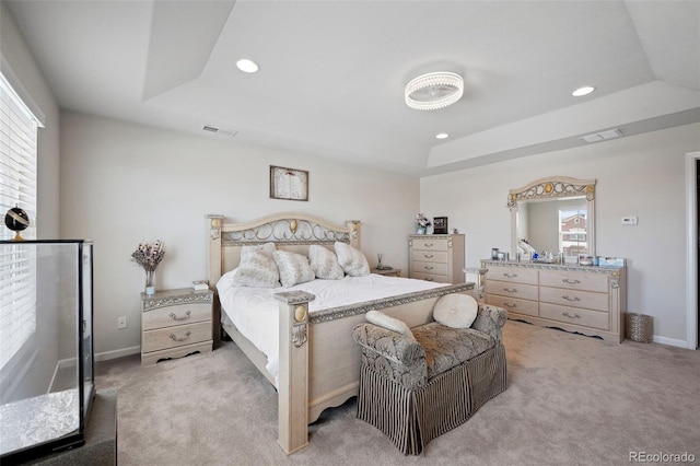 bedroom with light colored carpet and a raised ceiling