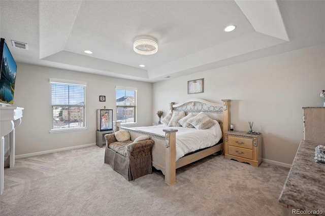 carpeted bedroom with a textured ceiling and a tray ceiling