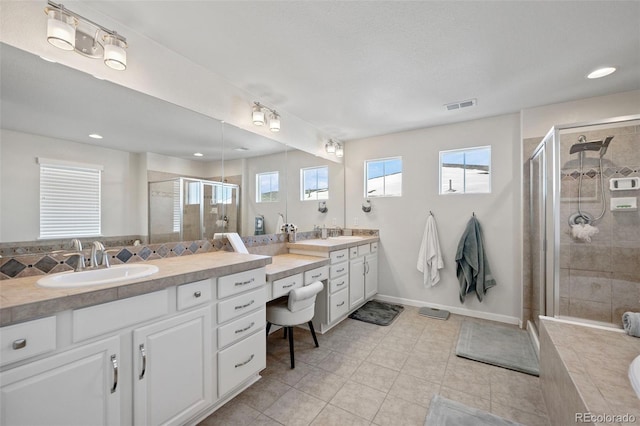 bathroom with a shower with door, vanity, plenty of natural light, and tile patterned flooring