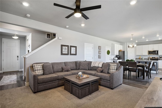 living area with ceiling fan with notable chandelier, stairs, recessed lighting, and light wood-type flooring