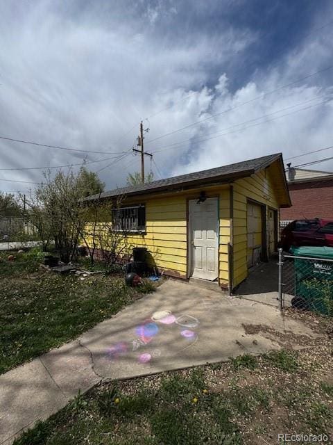 view of outdoor structure with fence and an outbuilding