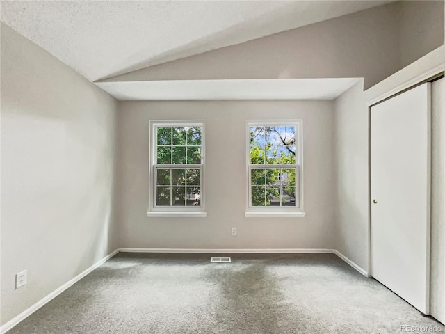 unfurnished bedroom featuring carpet flooring, a textured ceiling, and vaulted ceiling