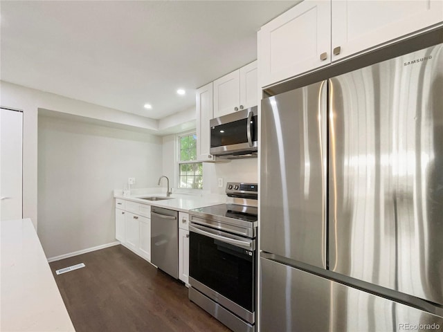 kitchen with dark hardwood / wood-style flooring, white cabinetry, sink, and appliances with stainless steel finishes