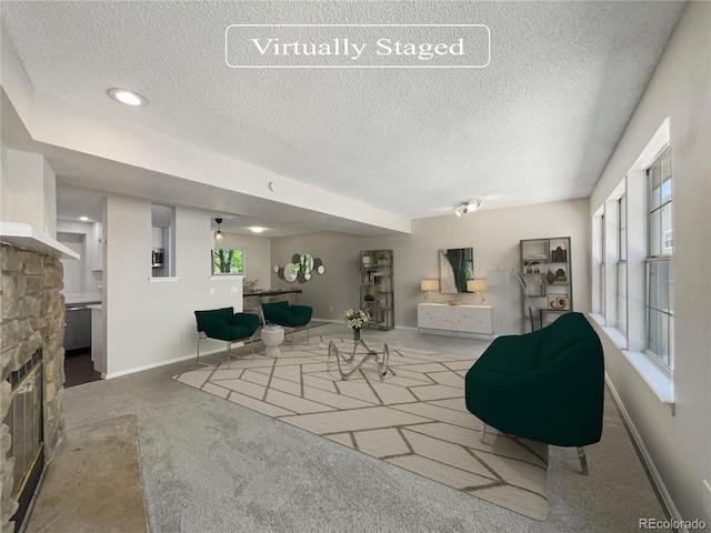 living room featuring carpet, a textured ceiling, and a stone fireplace