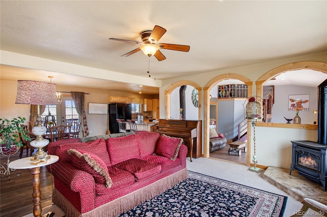 living room with ceiling fan and a wood stove