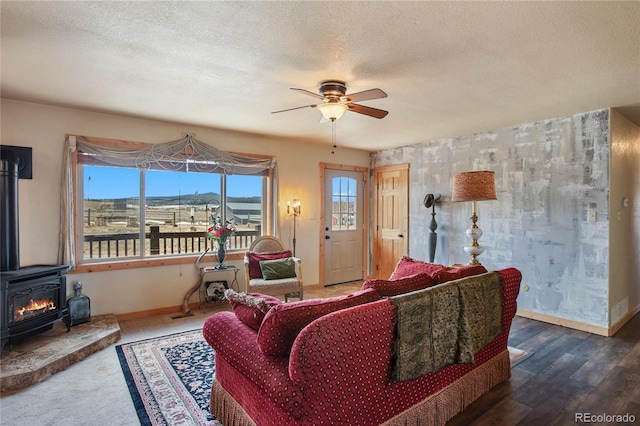 living room with hardwood / wood-style floors, a textured ceiling, a wood stove, and ceiling fan