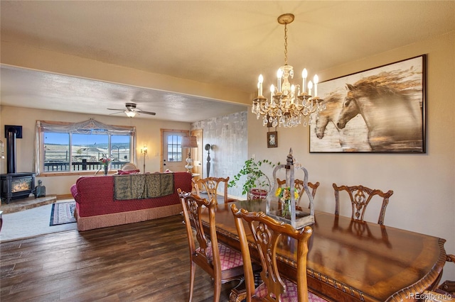 dining space with ceiling fan with notable chandelier, dark hardwood / wood-style flooring, and a wood stove