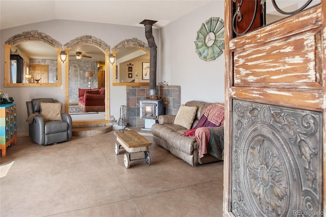 sitting room featuring ceiling fan, a wood stove, and lofted ceiling