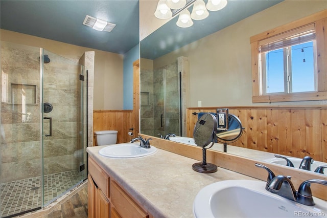 bathroom featuring toilet, wooden walls, vanity, a shower with shower door, and hardwood / wood-style flooring