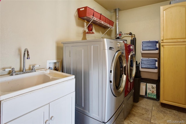 clothes washing area with separate washer and dryer, sink, and cabinets