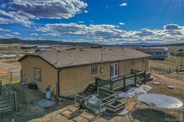 back of house featuring central AC, a trampoline, a deck with mountain view, and french doors