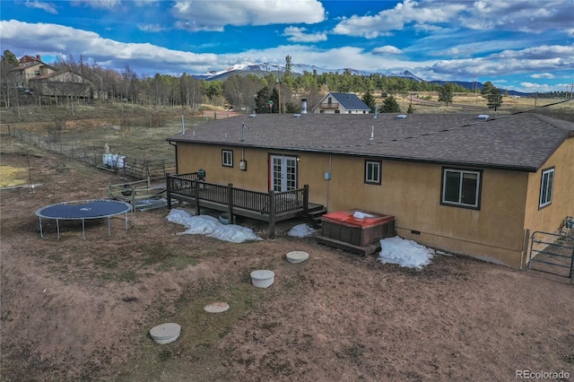 rear view of property with a deck with mountain view, a hot tub, and a trampoline