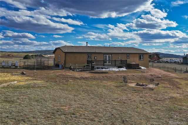 rear view of house with a deck with mountain view, a yard, and a trampoline