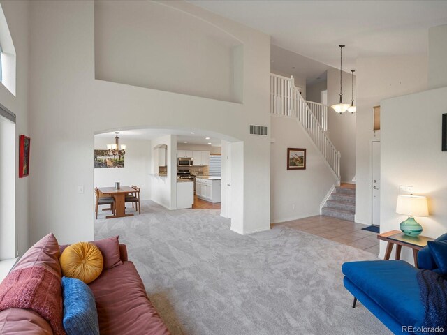 7400 W Grant Ranch Blvd Unit 19, Littleton, CO 80123 - living area featuring high vaulted ceiling, light colored carpet, a chandelier, stairway, and arched walkways