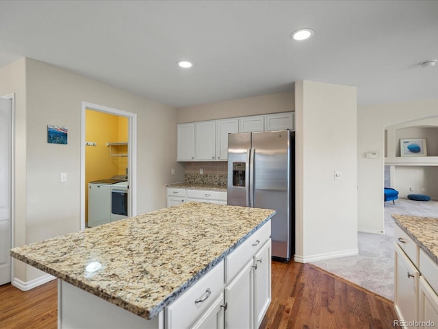 7400 W Grant Ranch Blvd Unit 19, Littleton, CO 80123 - kitchen featuring stainless steel fridge with ice dispenser, separate washer and dryer, white cabinetry, light stone countertops, and wood finished floors