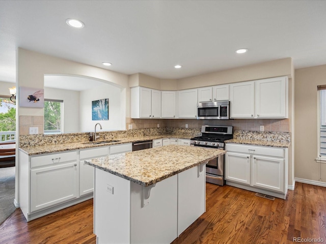 7400 W Grant Ranch Blvd Unit 19, Littleton, CO 80123 - kitchen with appliances with stainless steel finishes, a sink, a center island, white cabinetry, and dark wood-style floors