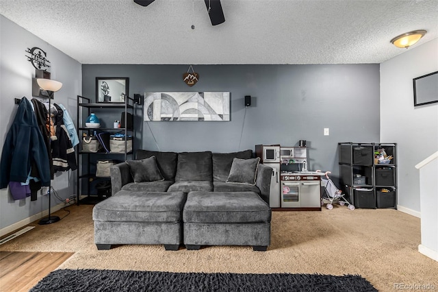 living room featuring ceiling fan, carpet, and a textured ceiling