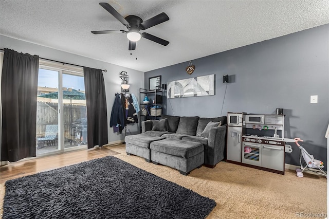 living room with ceiling fan, a textured ceiling, and light wood-type flooring