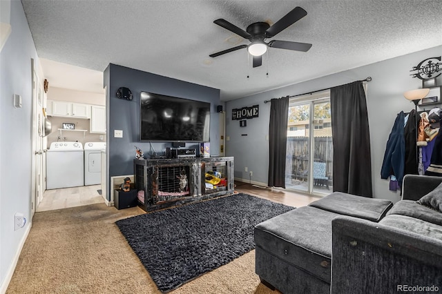 living room with a fireplace, washing machine and clothes dryer, light colored carpet, a textured ceiling, and ceiling fan