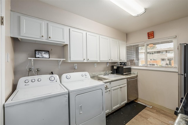 clothes washing area with washer and dryer, sink, and light hardwood / wood-style floors