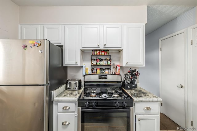 kitchen with white cabinets, stainless steel appliances, light stone counters, and a textured ceiling