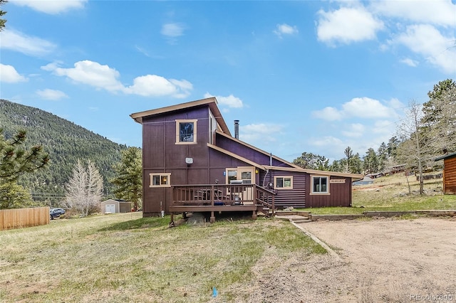 back of property with a shed, a yard, and a deck with mountain view