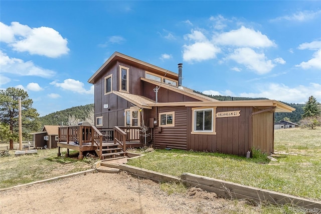 back of property featuring a wooden deck and a lawn