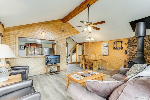 living room featuring lofted ceiling with beams, wooden walls, a wood stove, and hardwood / wood-style floors