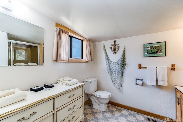 bathroom with toilet, vanity, and lofted ceiling