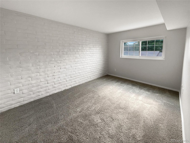 carpeted empty room featuring brick wall