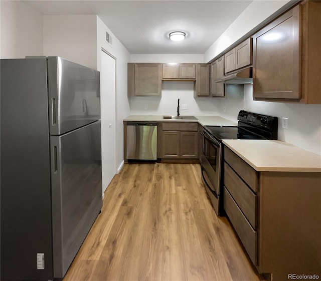 kitchen featuring stainless steel appliances, sink, and light hardwood / wood-style floors