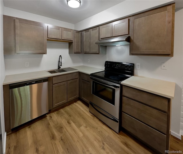 kitchen featuring stainless steel appliances, sink, and light hardwood / wood-style flooring