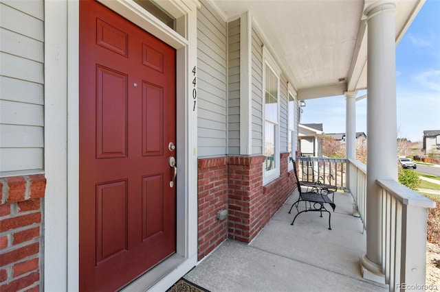 entrance to property with covered porch and brick siding