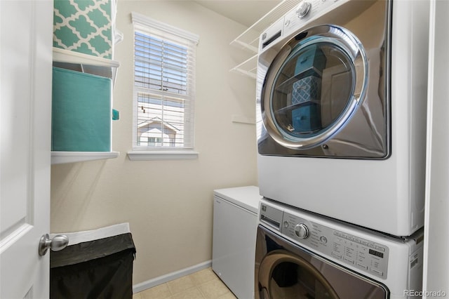 clothes washing area with stacked washer / dryer and baseboards