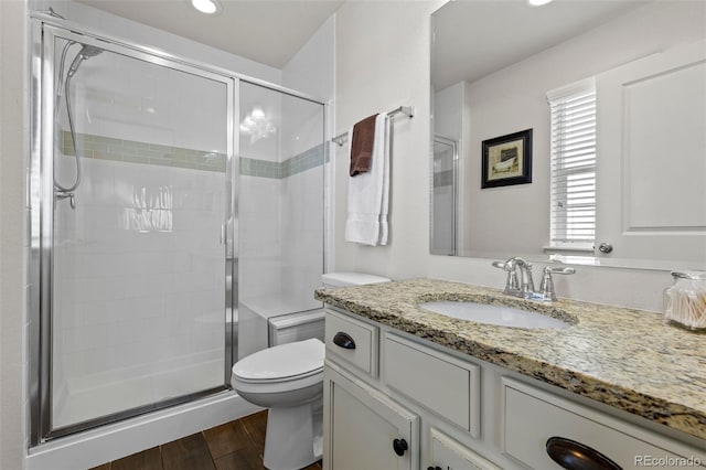 bathroom featuring a shower stall, toilet, wood finished floors, vanity, and recessed lighting