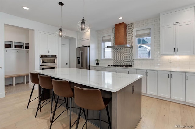 785 Delechant Dr, Erie, CO 80516 - kitchen featuring stainless steel appliances, wall chimney range hood, decorative backsplash, a center island, and white cabinets